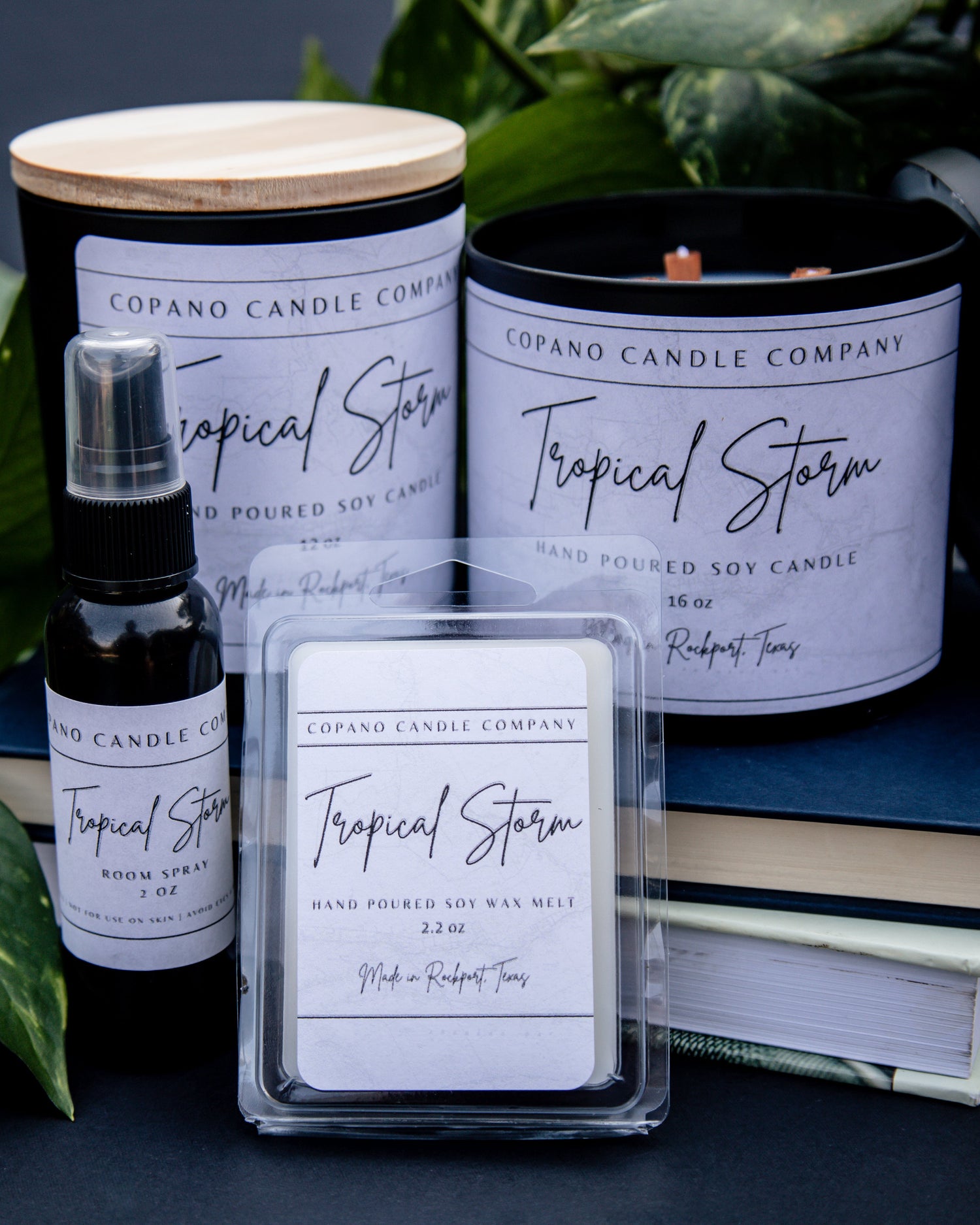 Copano Candle Company candles, room spray, and wax melts on a dark surface with greenery